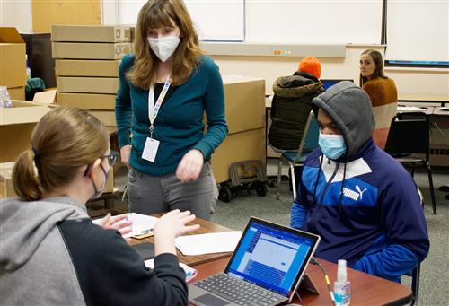 student working on computers with teachers