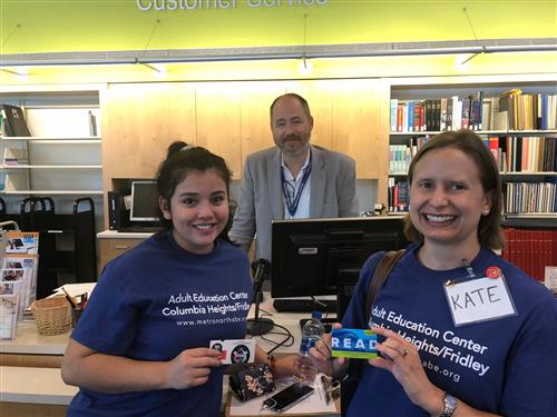 Volunteer and student standing with librarian in library. 