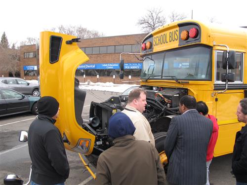 Students examining the engine of a bus 