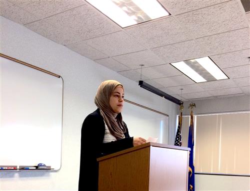 Mannar stands at the podium giving her speech. 