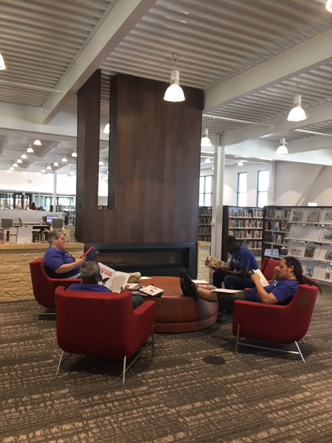 Students sitting in library chairs reading. 