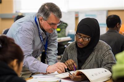 Volunteer and student looking at book together. Volunteer and student looking at book together.